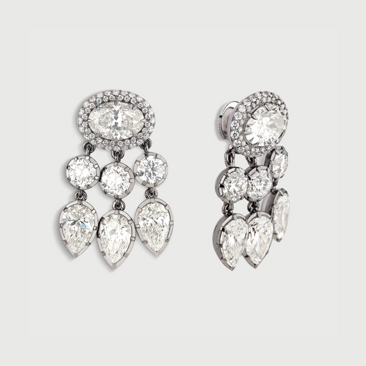 Pair of silver earrings with clear gemstones on a light gray background