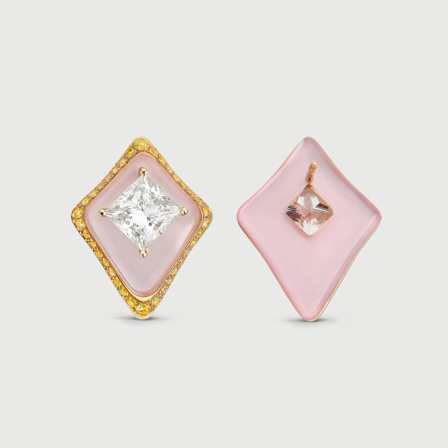 Pair of earrings with pink square stones and gold accents on a light gray background