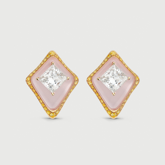 Pair of diamond-shaped earrings with pink centers and gold frames on a light gray background