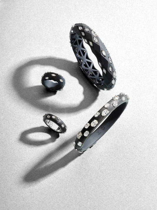 Black rings and bracelets with gemstones on a light gray background