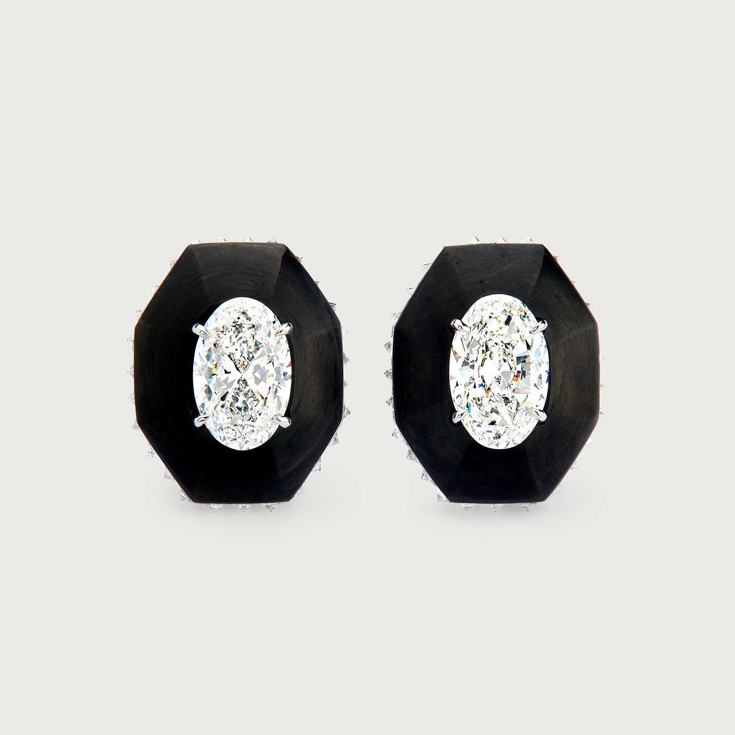 Pair of black stud earrings with clear gemstones on a light gray background