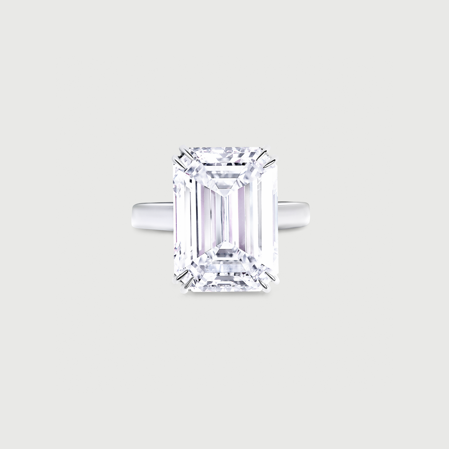 Diamond ring with emerald-cut gemstone on a light gray background
