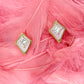 Pair of diamond earrings on pink feathers